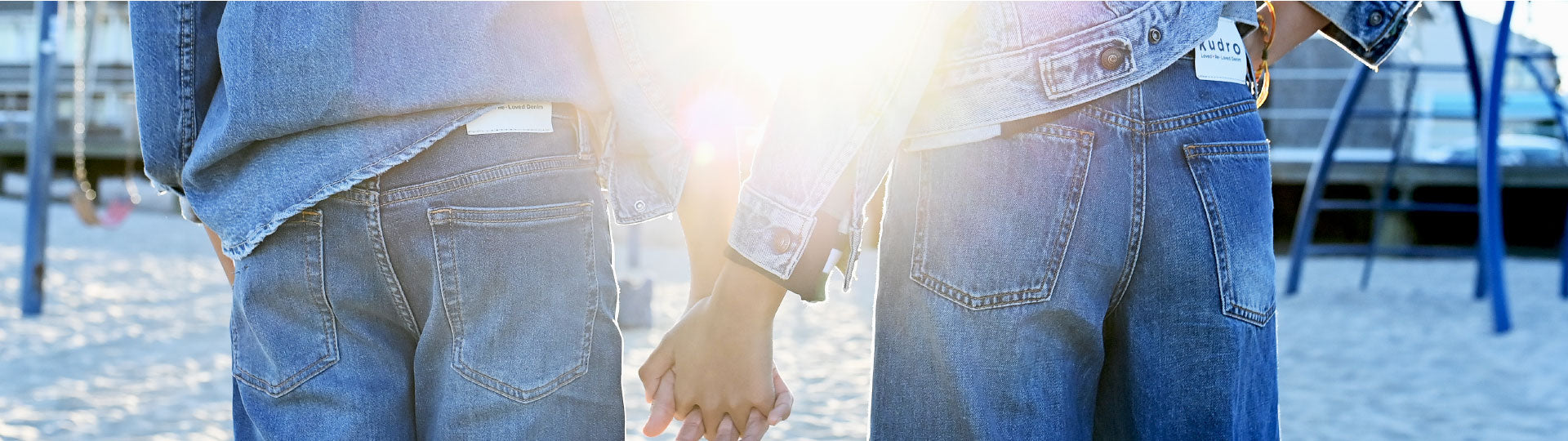 Children holding hands at sunny beach wearing Kudro Kids denim jeans collection