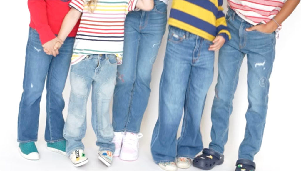 Five pairs of kudro kids  jeans worn by kids on a white background