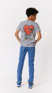 boy wearing a gray t-shirt with a red heart on a skate board graphic and blue jeans on a white background